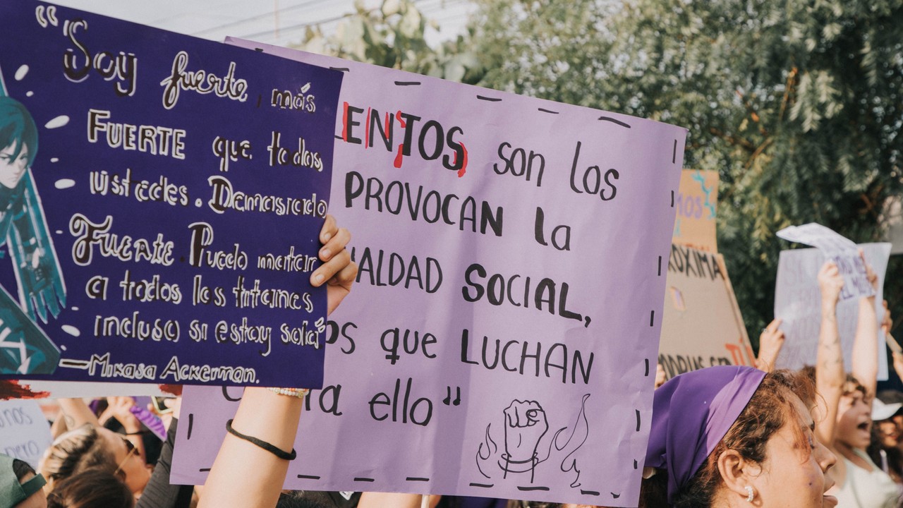 Women hold placards during an outdoor demonstration.