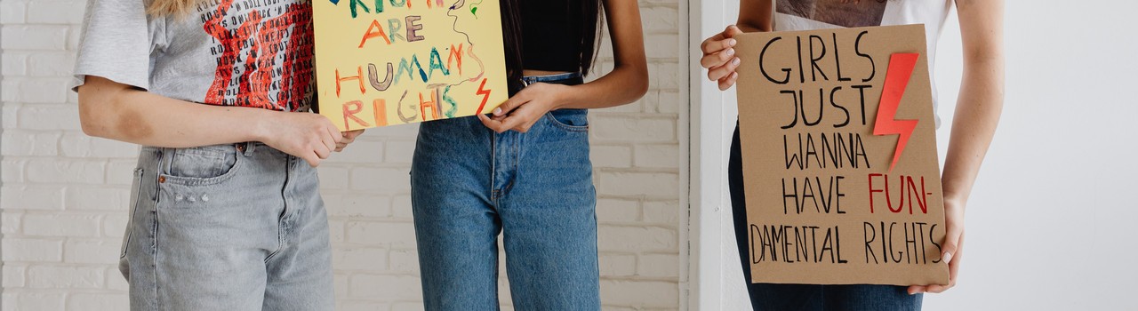 Hands hold two hand-lettered placards about fundamental rights.