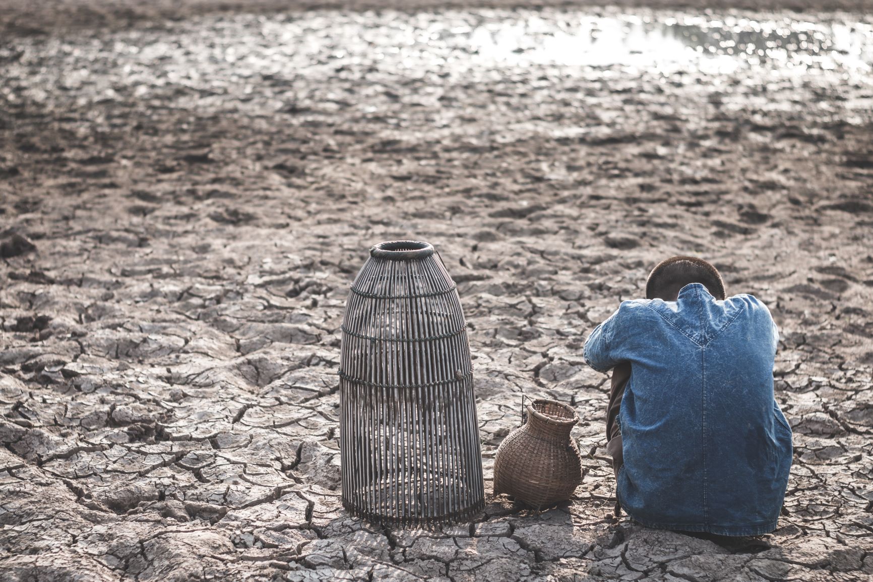 Person sitting on cracked soil