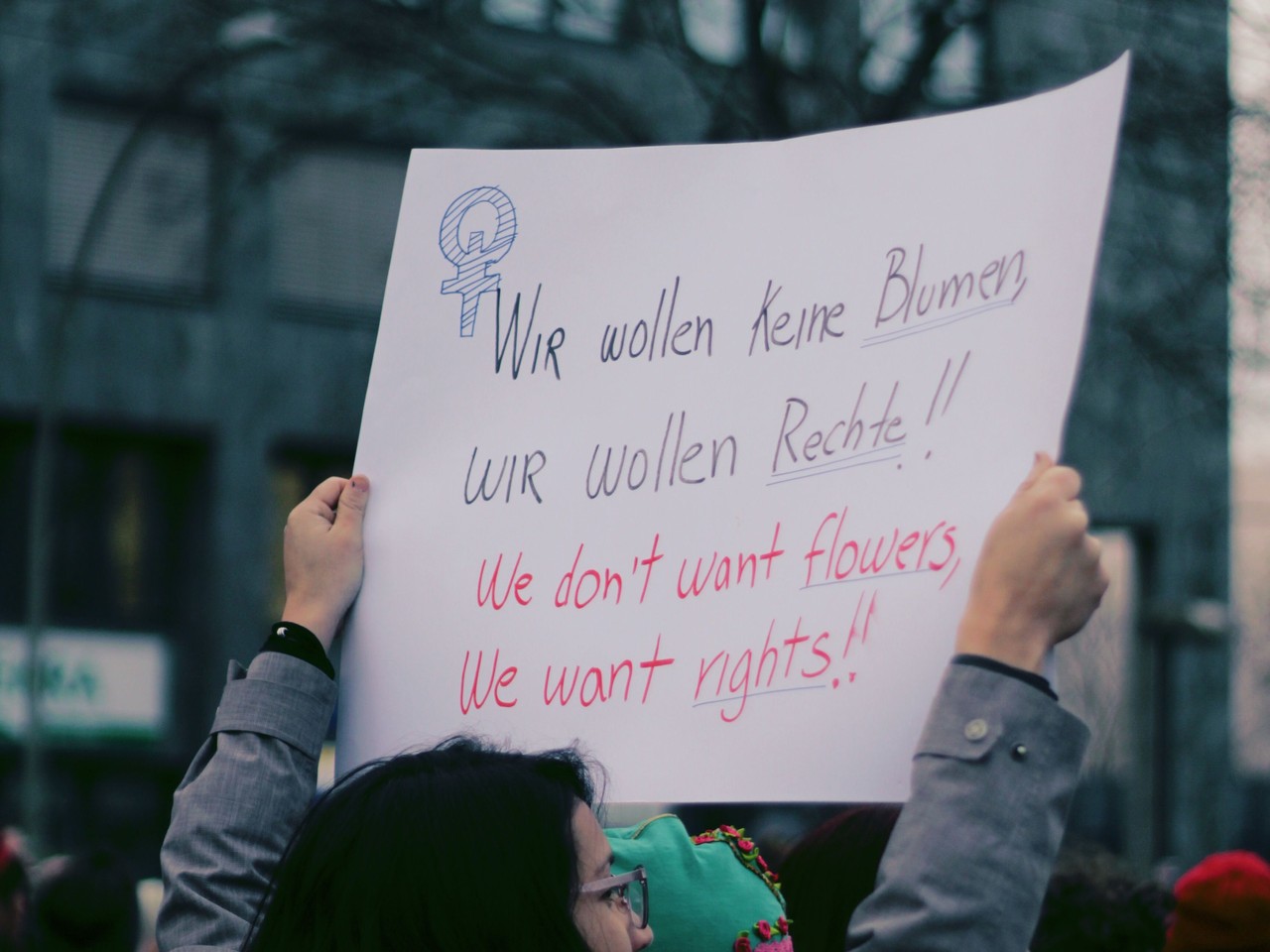 A person raises a hand-lettered sign calling for women’s rights at a demonstration.