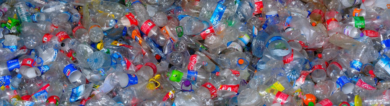 A dense pile of colourful discarded plastic bottles fills the frame.